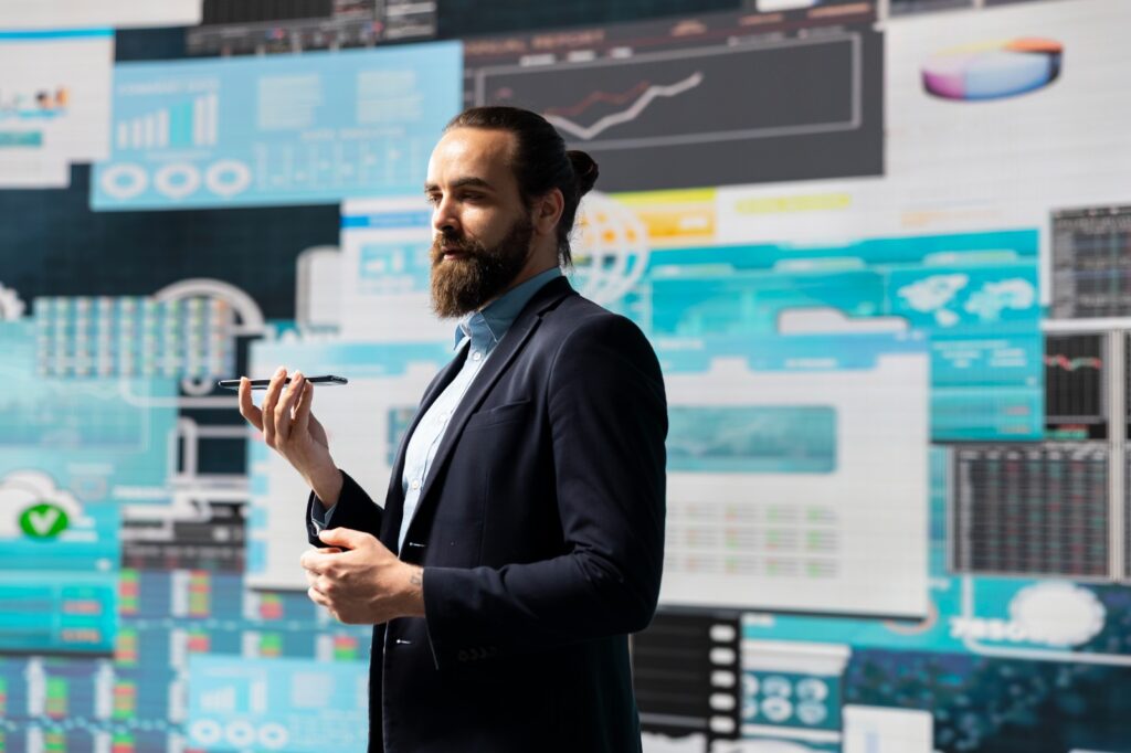 Executivo em frente a uma parede de painéis digitais com gráficos, indicadores e mapas de dados corporativos.